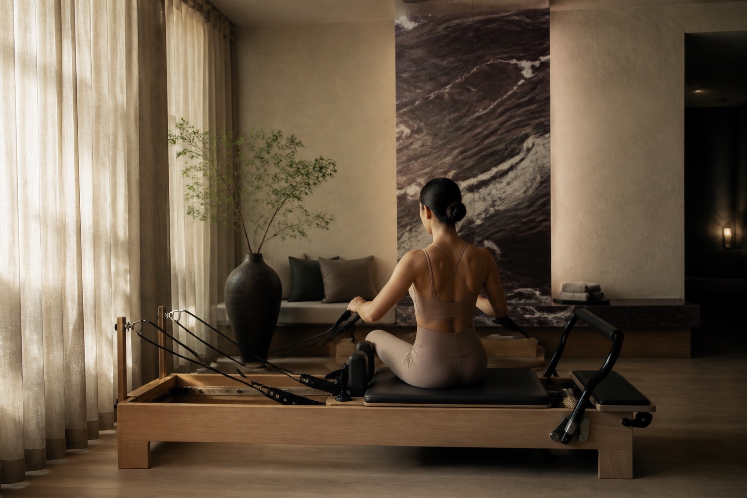 Reformer Pilates suite with linen curtains, warm lighting and deep plum marble accents